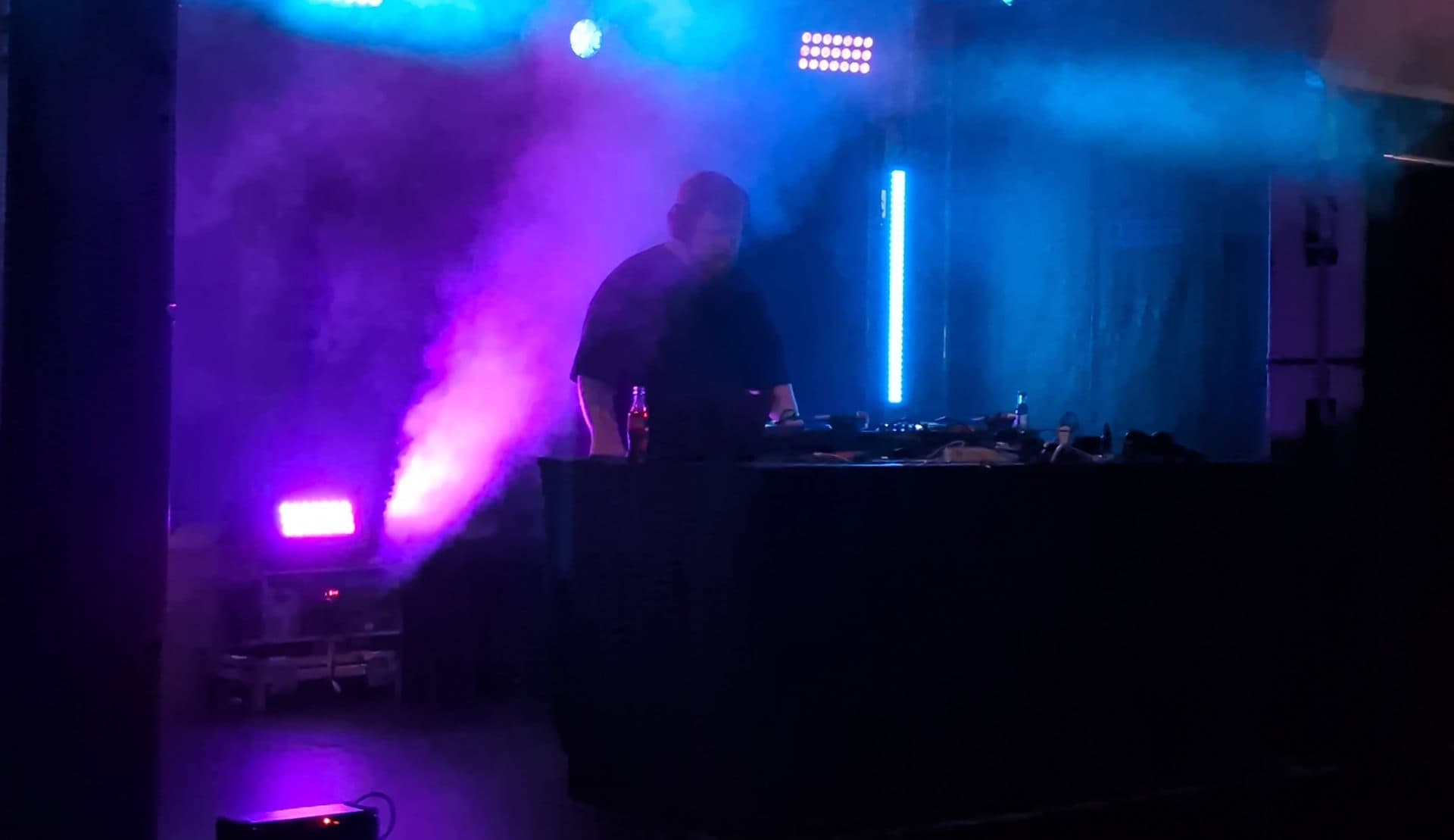 DJ im farbigen Bühnennebel bei einer Veranstaltung der THE MALAMUTE Bar & Gallery