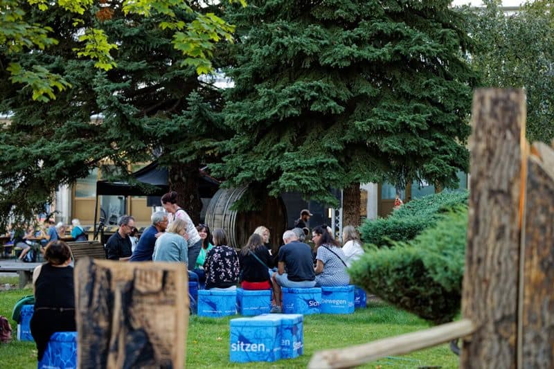 Gäste sitzen im grünen Innenhof des MONOPOL Leipzig zusammen