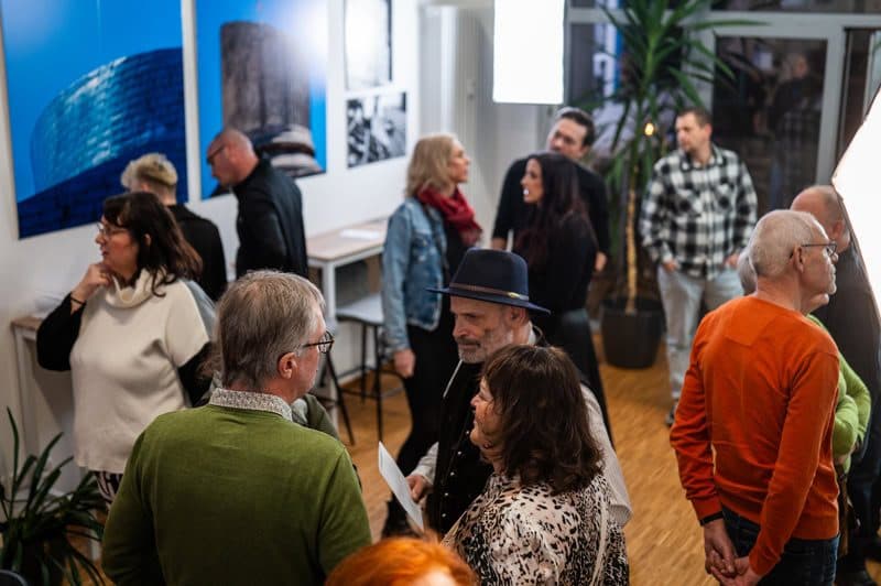 Vernissage „Von Wegen und Geschichten“ – Gäste vor großformatigen Fotografien