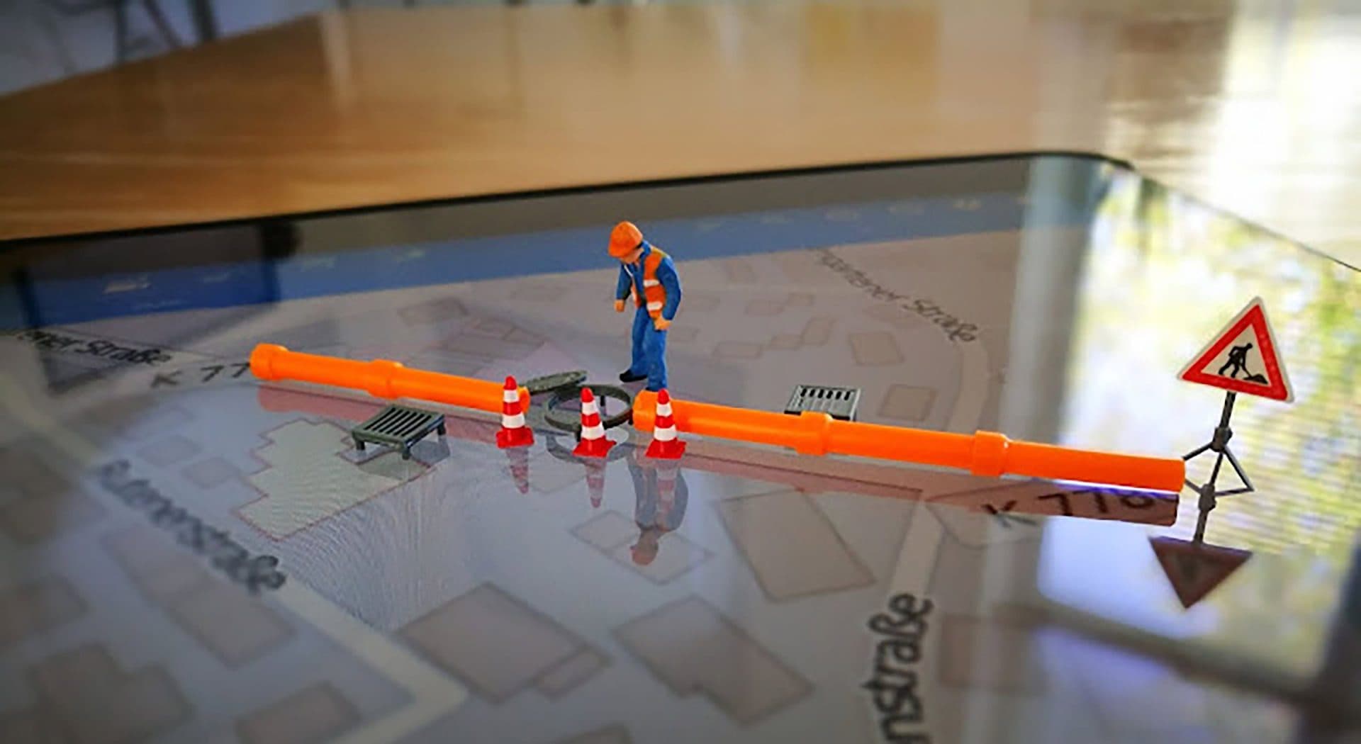 Miniaturfigur eines Bauarbeiters mit Absperrung und Warnschild auf einem Stadtplan