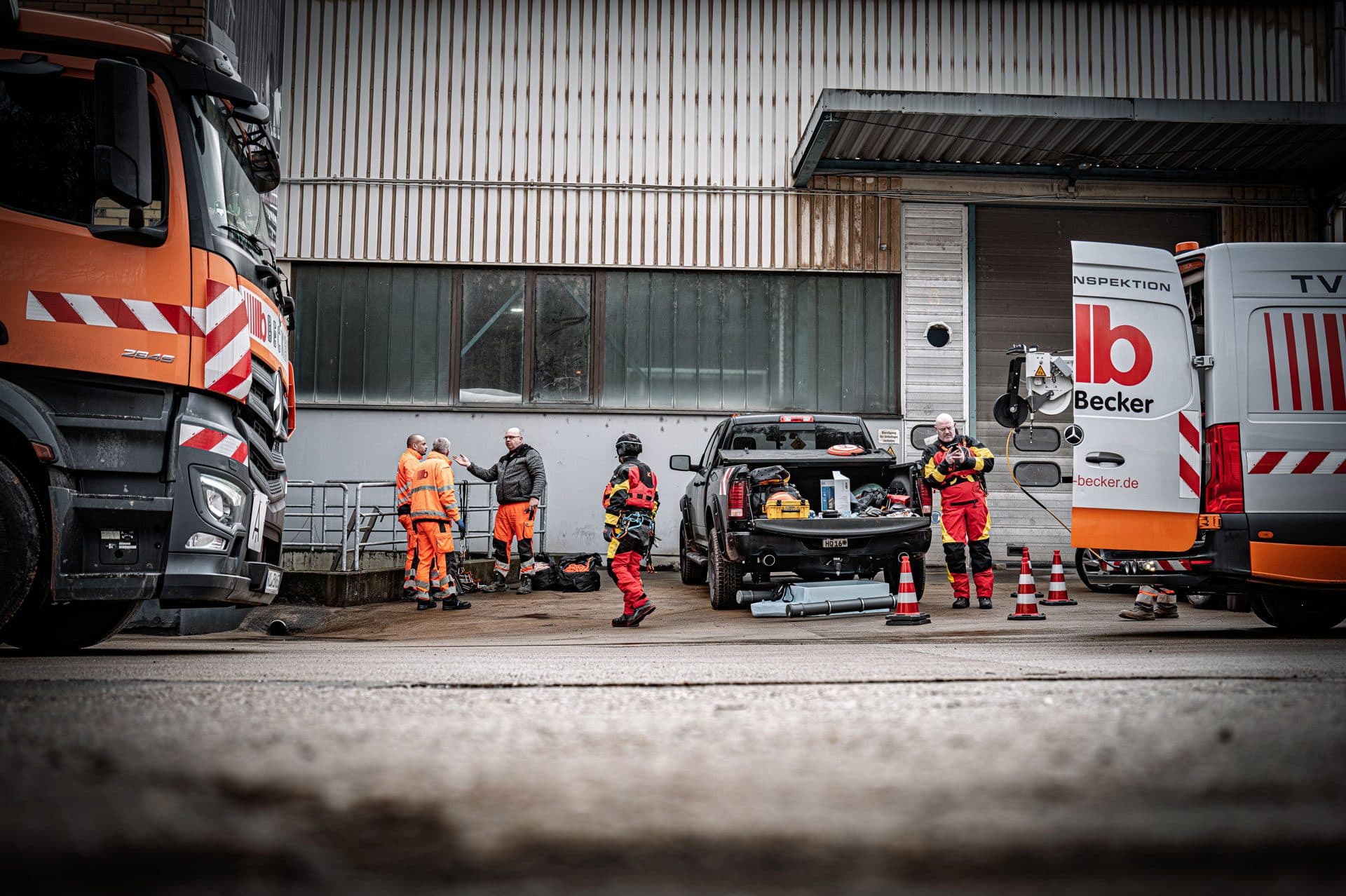 Inspektionsteam in Warnkleidung vor Einsatzfahrzeugen bei der Vorbereitung einer Kanalinspektion